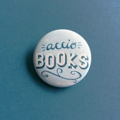 a white button with the words acio books on it sitting on a blue surface