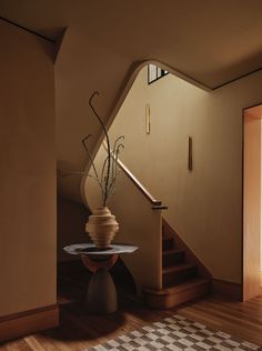 a vase with flowers on top of a table in front of a stair case next to a window