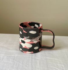 a black and pink coffee mug with white polka dots on the inside is sitting on a table