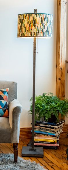 a lamp sitting on top of a wooden floor next to a chair and a potted plant