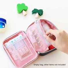 a person is opening an empty pink travel bag on a white table with other items