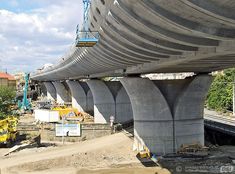 construction is being done on the side of a large bridge overpass in an urban area