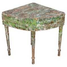 an old wooden table with green paint on it's top and legs, sitting in front of a white background