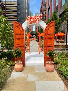 an orange and white arch with the word aprrol spirit on it in front of some buildings