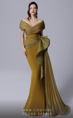 In this MNM COUTURE 2692 creation, ascend to a whole new level of sophistication. This gown has fine pleats on panels that wrap into a surplice design. Structured with an off shoulder neckline on a corset defined bodice and nipped with a tonal belt, the waist is graced with a voluminous ruffle at one side. Pleats drape the skirt, forming a mermaid silhouette with a cascading sash and a sweeping train. Make your presence known in this MNM COUTURE masterpiece. Models are wearing the Fuchsia, Olive Olive Gown, Plus Size Gowns Wedding, Fouad Sarkis, Mnm Couture, Off Shoulder Gown, Mermaid Evening Gown, Plus Size Gowns, Gown Plus Size, Mermaid Fashion