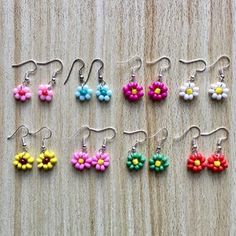 small flower earrings are displayed on a wooden surface, with the word love spelled in white letters