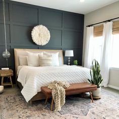 a bedroom with a bed, chair and potted plant on the floor in front of it