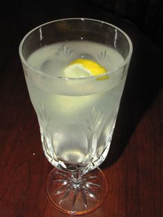 a glass filled with liquid and a lemon wedge on top of the drink in it