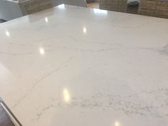 a white marble counter top with wicker chairs in the backgroung behind it