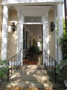 an entry way to a house with white pillars and black railings on both sides