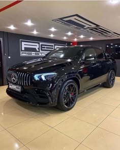 a black mercedes suv parked in a showroom