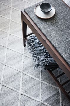 a table with a plate on top of it next to a gray rug and chair