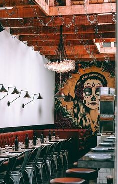 the interior of a restaurant with tables, chairs and artwork on the wall behind them