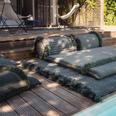 a set of cushions sitting on top of a wooden deck next to a swimming pool