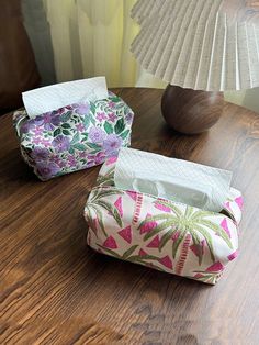 two tissue boxes sitting on top of a wooden table