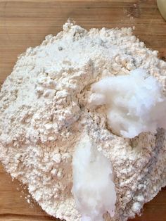 a wooden cutting board topped with lots of white powdered sugar and an apple next to it