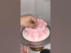 someone is decorating a cake with pink icing