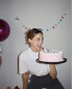 a woman holding a birthday cake with candles on it