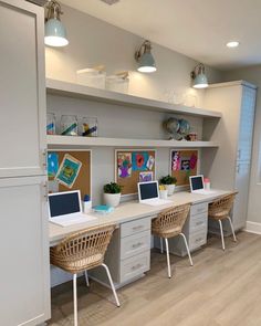 an office with two desks and three laptops on the same desk in front of some shelves