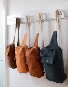 four purses hanging on the wall in a row with one bag attached to it