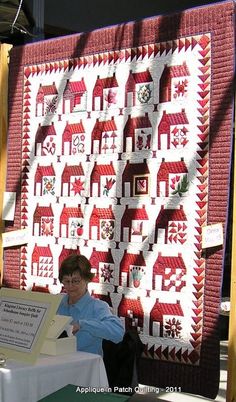 a woman standing next to a table with a quilt on it