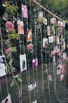 many pictures are hung on a string with pink flowers and photos hanging from the strings