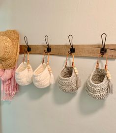 four crocheted baskets hanging on a wall with tassels attached to them