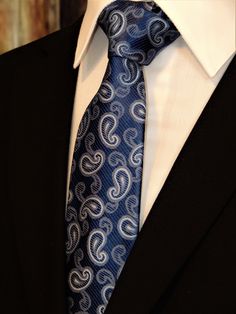 "Mens 100% silk blue paisley necktie. This Blue paisley tie features a navy background with blue ourlined with off white paisley pattern. Handmade from 100% silk, this special collection features a .75\" Eds Neckties logo at the bottom right front corner of every tie and a larger logo located on the tipping (Back of the tie). The label features the collection name (Nathaniel Alexandria) Named after my son Nathaniel and my daughter Alexandria. Expertly hand-made from 100% silk you can select your Purple Gothic, Make A Tie, Blue Necktie, Floral Necktie, Suit Ideas, Goth Wedding, Paisley Tie, Fashion Suits For Men, Navy Background