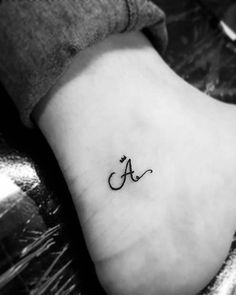 a small tattoo on the foot of a woman's foot, with an initial