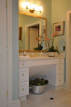 there is a bowl full of flowers on the counter in front of the bathroom sink