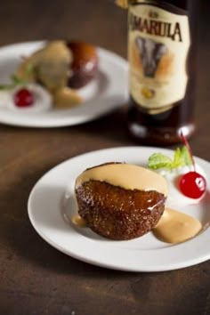 two white plates topped with desserts next to a bottle