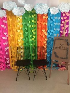 two chairs in front of a rainbow backdrop with clouds and hearts on the back wall