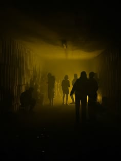 silhouettes of people walking through a tunnel in the dark with light coming from behind