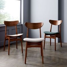 two wooden chairs sitting next to each other in front of a window on top of a hard wood floor