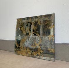 a mirror sitting on top of a wooden floor next to a white wall with yellow and black paint