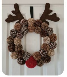 a christmas wreath with reindeer antlers hanging on the front door, decorated with brown and red balls