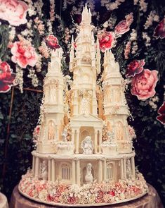 an instagram photo of a cake with flowers on the side and a castle in the middle