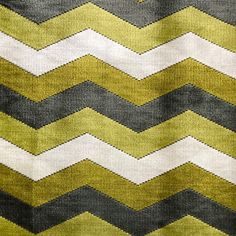 a yellow and grey rug with white stripes on it's edges, in the shape of zigzag