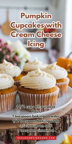 pumpkin cupcakes with cream cheese icing on a white plate next to flowers