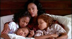 three women and two children laying in bed together