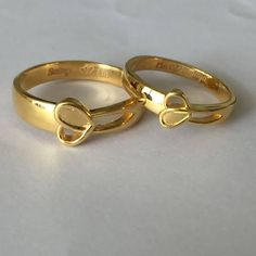 two gold wedding rings on a white surface