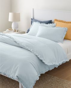 a white bed with blue sheets and yellow pillows