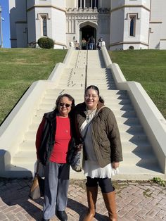 two women standing in front of a large white building with steps leading up to it