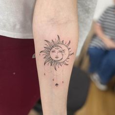 a woman's arm with a sun and moon tattoo on it, in black ink