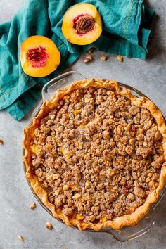 a pie sitting on top of a table next to sliced peaches