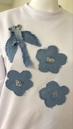 a white t - shirt with blue flowers on the front and back, made out of old jeans