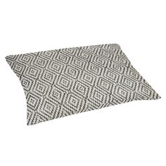 a black and white pillow sitting on top of a white floor mat with a diamond pattern