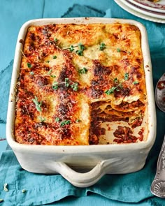 a casserole dish with meat and cheese in it on a blue table cloth