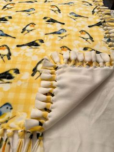 a yellow and white table cloth with birds on it, sitting on top of a bed