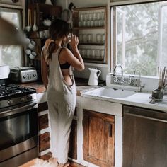 a woman standing at the sink in a kitchen looking out over the counter to the outside